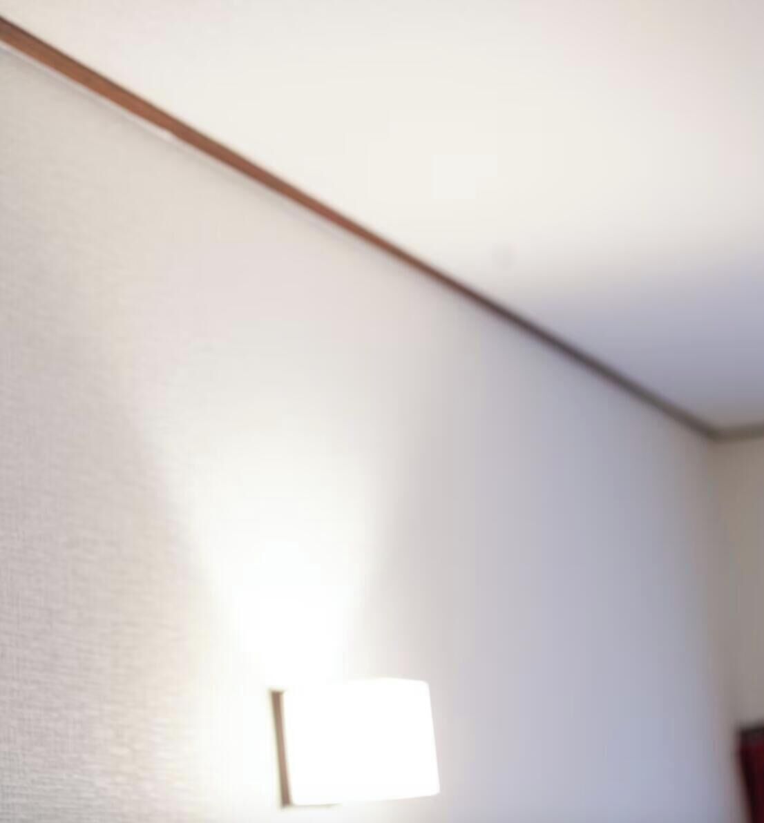 A room with a white wall, a wooden trim, and a light fixture.