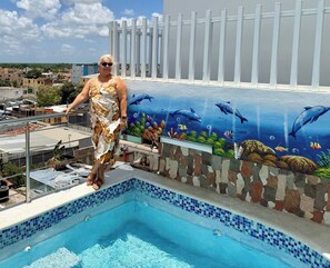 A person standing by a pool with a mural of marine life. - Apartamento 4 Hotel María Bonita Higüey (Higuey)