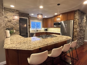 A kitchen with granite countertops, a stainless steel refrigerator, wooden cabinets, and a stone accent wall. - Luxury Keystone Retreat 4 Bed/4 Bath, Slope Views & Fast Ski Access (Keystone)