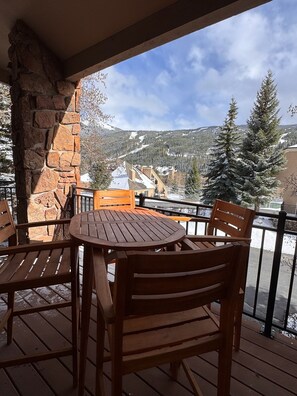 A wooden deck with a stone wall, a round table, and four wooden chairs. - Luxury Keystone Retreat 4 Bed/4 Bath, Slope Views & Fast Ski Access (Keystone)