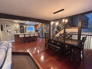 A modern kitchen with a stone backsplash, a dining area with a wooden table and chairs, and a staircase leading to an upper level. - Luxury Keystone Retreat 4 Bed/4 Bath, Slope Views & Fast Ski Access (Keystone)