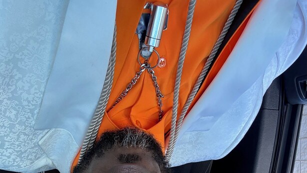 En person som ligger ner med ett bilbarnstolsöverdrag och ett vitt och orangefärgat tyg.