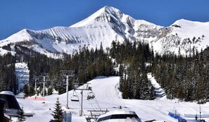 A snow-covered mountain with a ski lift and trees. - Cozy Mountain Condo in Big Sky – Steps from Adventure (Big Sky)