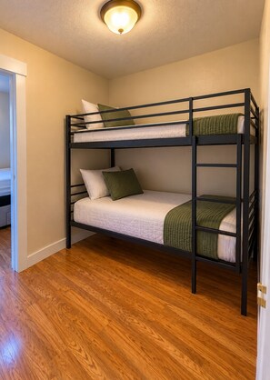 A bunk bed with two levels, a wooden floor, and a ceiling light fixture. - Cozy Mountain Condo in Big Sky – Steps from Adventure (Big Sky)