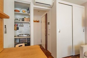 A compact kitchen with a microwave, stove, and shelves with kitchenware. - Trastevere Petite Escape (Roma)