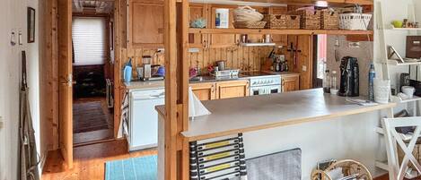 A compact kitchen with wooden cabinets, a white countertop, and a built-in stove.