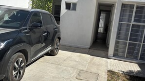 En svart SUV står parkerad på en uppfart framför en vit byggnad med ett grönt tak och en vattentank på taket.