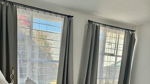 Ett hotellrum med en säng, kuddar, ett sängbord, en lampa och utsikt över omgivningen.