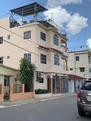 Um edifício residencial com vários andares, telhado plano, várias janelas e portão fechado.