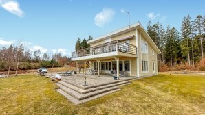 Ein zweistöckiges Haus mit Balkon, Auffahrt und Rasenfläche.