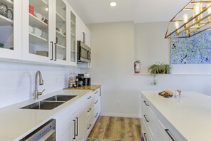 Une cuisine moderne avec des meubles blancs, des appareils en acier inoxydable et un plan de travail en bois.