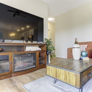 A living room with a flat-screen TV, wooden cabinet, fireplace, and decorative vases. - Unwind Centrally located in the heart of Canadas most beautiful Wine region (West Kelowna)