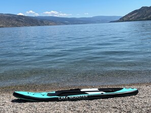 Un kayak sur une plage de galets, avec un lac et des collines en arrière-plan.