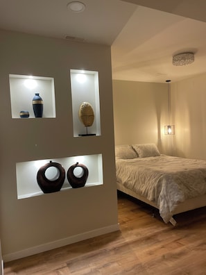 Un dormitori amb un llit, una tauleta de nit i prestatges fixats a la paret amb objectes decoratius.