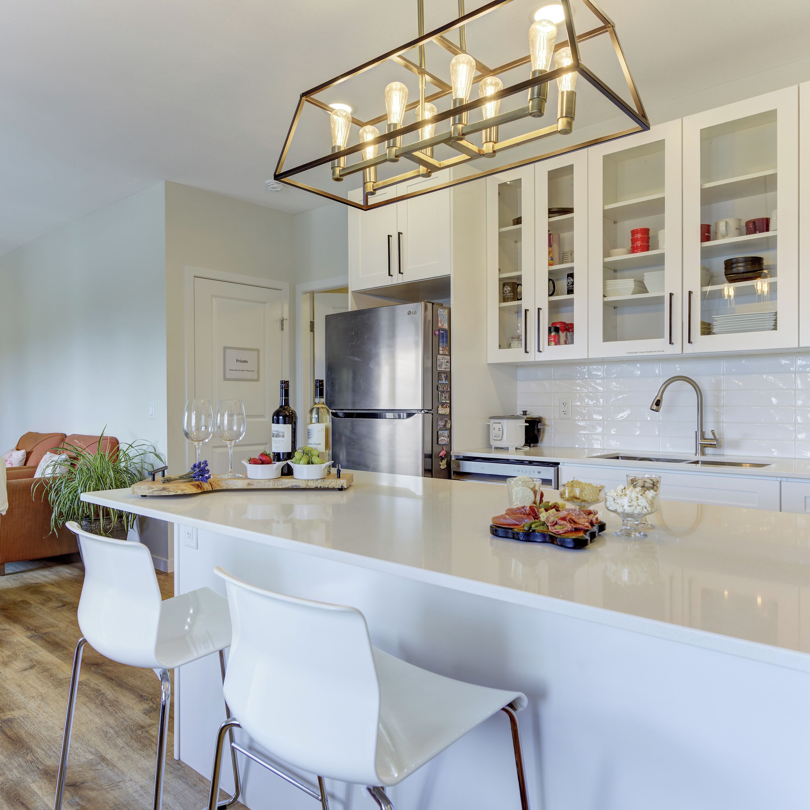 A modern kitchen with a central island, white cabinetry, and stainless steel appliances.