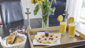 A breakfast tray with pastries, a glass of orange juice, and a vase with sunflowers.