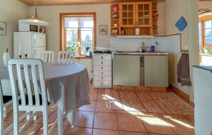 Cuina amb taula de menjador, cadirees, armaris i una finestra.