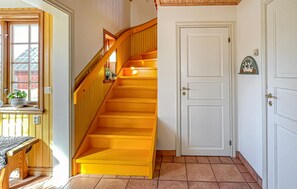 A staircase with a wooden handrail and a white door with a small decorative item above it.