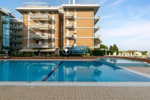 Ein modernes Apartmenthaus mit Schwimmbad, Balkonen und blauem Himmel.