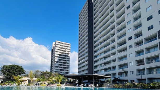A swimming pool with clear water, surrounded by modern buildings and a clear sky. - Beautiful apartment in Santa Marta closer to airport with view at the sea (Santa Marta City)