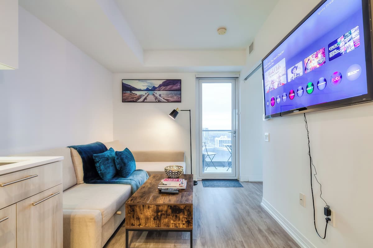 Una sala de estar moderna con un sofá, una mesa de centro y un televisor de pantalla plana que muestra servicios de streaming.