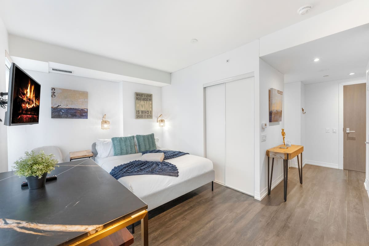 Un dormitorio moderno con cama, mesitas de noche, televisión y obras de arte en las paredes.