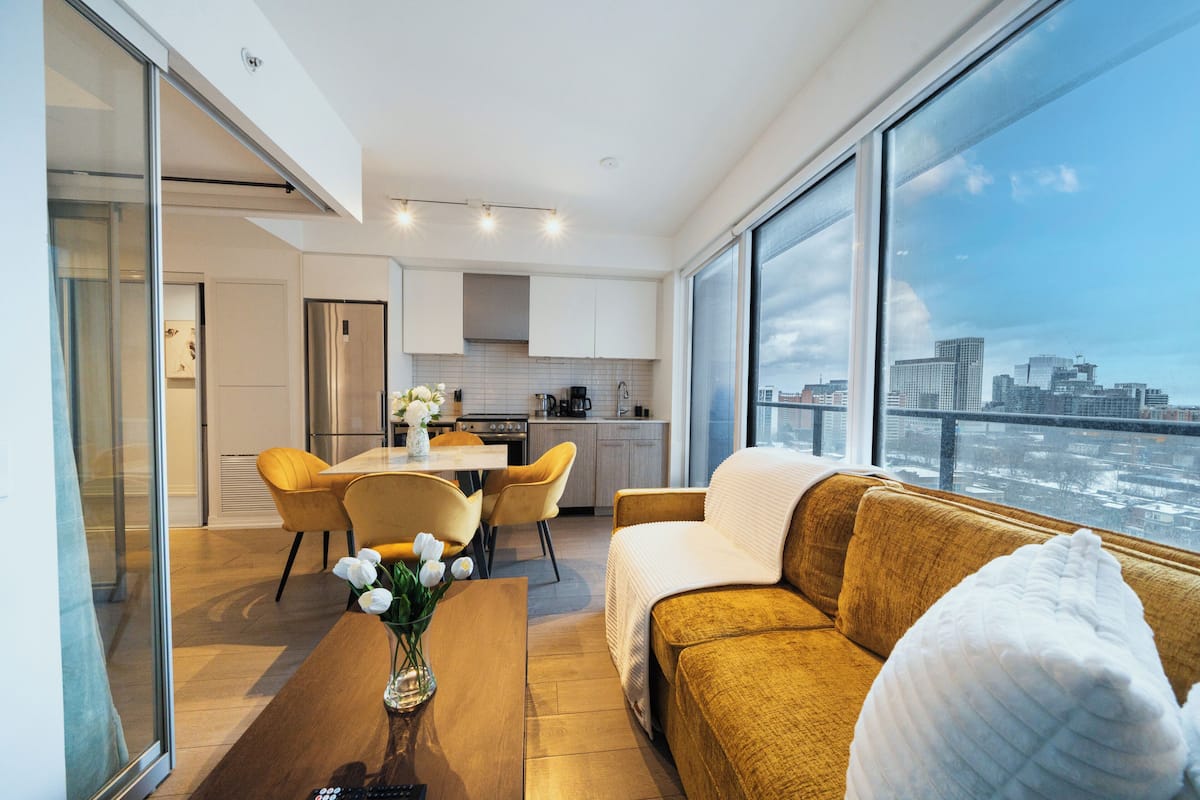 Una cocina moderna con zona de comedor, un sofá y vistas a un paisaje urbano.
