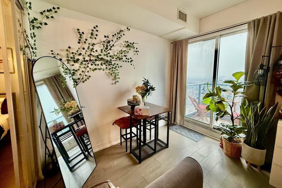 Una sala de estar moderna con comedor, ventanas amplias y plantas de interior.