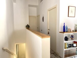Ein Korridor mit Holzbalken, einer Tür und einem Regal mit Büchern und Dekoration.
