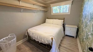 A bedroom with a bed, a nightstand, a ceiling fan, a window, and a laundry basket. - Spacious & Cozy 3BR | Perfect for Families (Augusta)