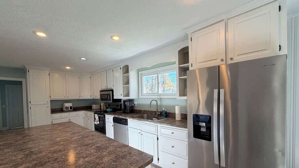 A modern kitchen with white cabinetry, a stainless steel refrigerator, and a granite countertop. - Spacious & Cozy 3BR | Perfect for Families (Augusta)