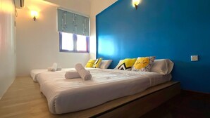 Een slaapkamer met twee bedden, een raam en een blauwe muur.