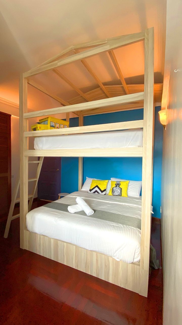 A bunk bed with a ladder, a blue wall, and a wooden floor.
