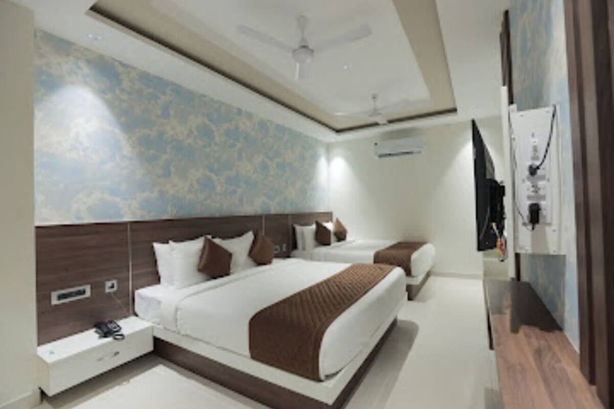 A modern hotel room with a large bed, a bedside table, a nightstand, a ceiling fan, and a wall-mounted TV.