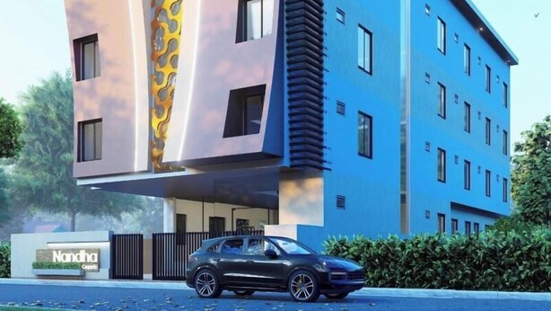 A modern hotel building with a unique giraffe design on the facade, multiple windows, and a car parked in front. - Nandha Grande (Udumalaipettai)