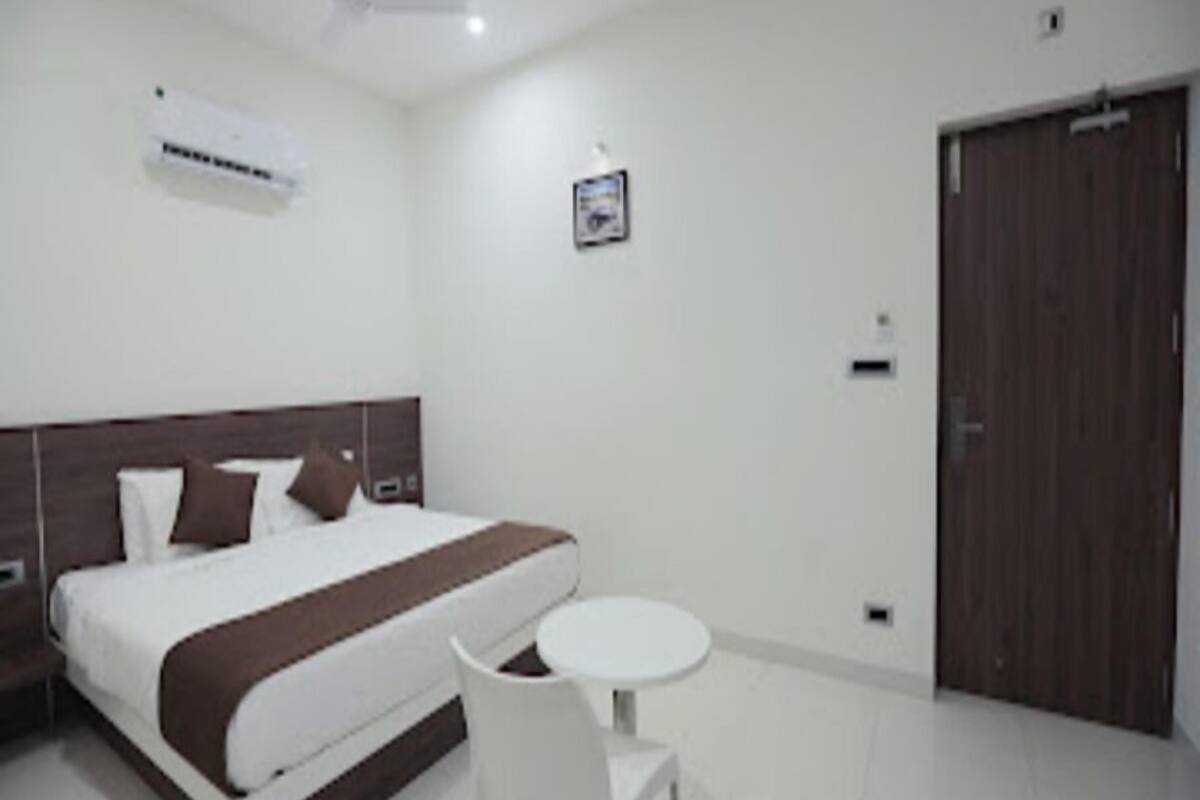 A hotel room with a bed, a bedside table, a chair, a ceiling fan, and a door.