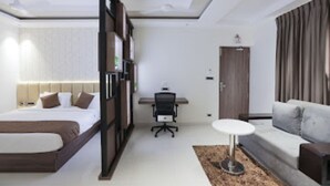 A modern hotel room with a bed, desk, and sofa. - Nandha Grande (Udumalaipettai)