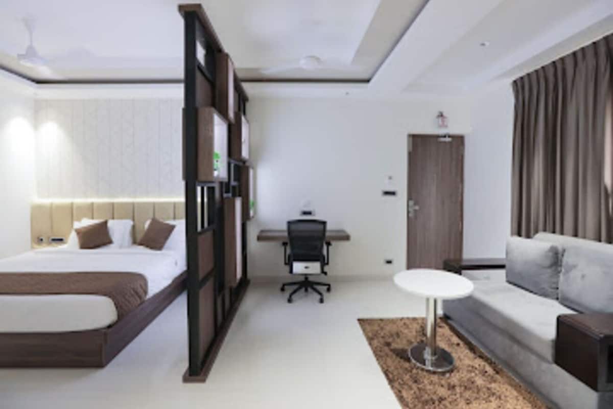 A modern hotel room with a bed, desk, and sofa.