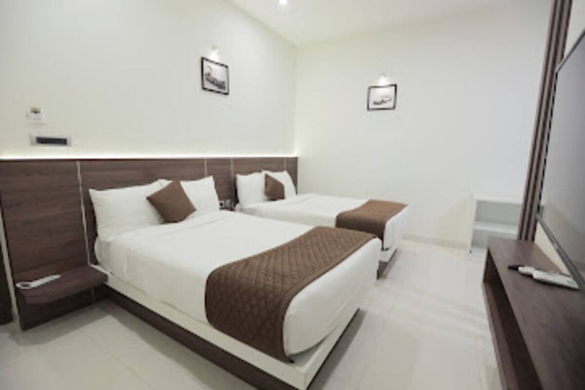 A hotel room with two beds, a desk, and a TV.