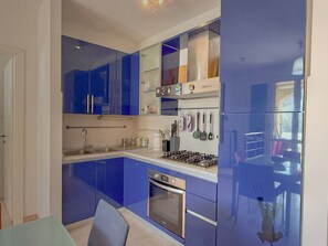 A modern kitchen with blue cabinets, stainless steel appliances, and a small dining area. - Two-room apartment Limonaia in Marina di Campo (Marina di Campo)