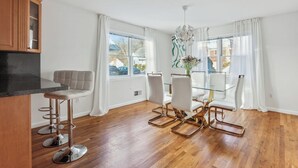 A modern kitchen with a wooden countertop, a bar stool, and a dining table with chairs.