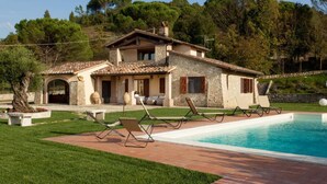 A villa with a swimming pool, outdoor seating, and a stone facade. - Umbria Genius Loci Farmhouse (Collazzone)