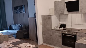Una cocina moderna con armarios grises, horno empotrado y zona de comedor con mesa para cuatro.