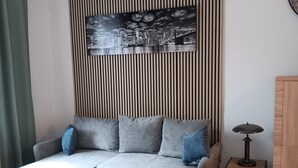 Una sala de estar moderna con un sofá seccional, una mesa de centro, una mesita auxiliar y un cuadro colgado en la pared.