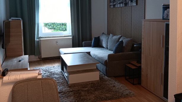 Una sala de estar moderna con un sofá, una mesa de centro y una mesa de comedor con un mantel individual.