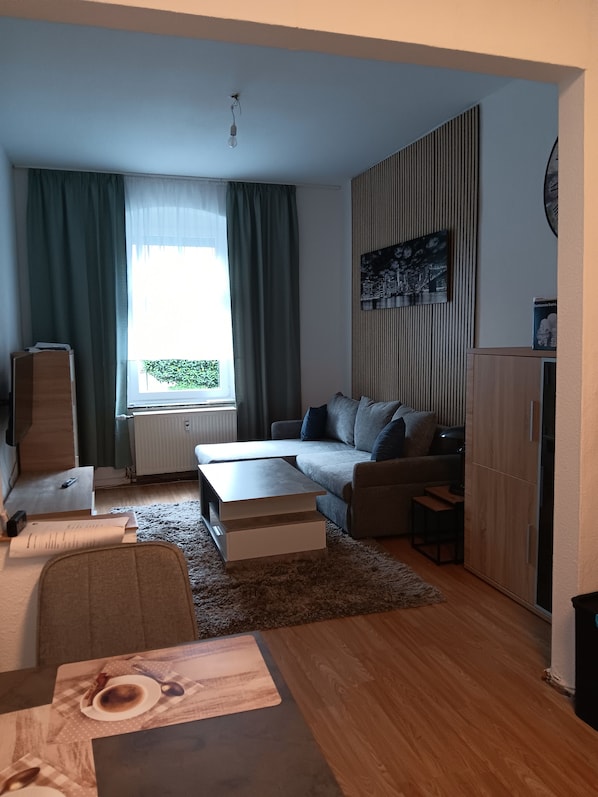 Ein modernes Wohnzimmer mit einer Couch, einem Couchtisch und einem Esstisch mit Platzdeckchen.