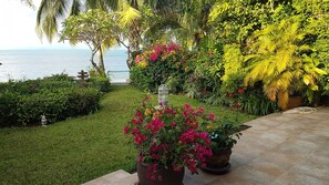 Un jardín con una fuente, plantas en macetas y vistas al mar.