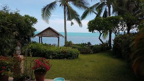 Un jardín con un pabellón, palmeras y vista al mar.