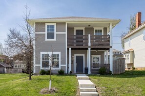 A two-story house with a front porch, a small front yard, and a visible mailbox.