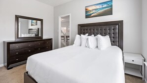 Une chambre à coucher avec un grand lit, une commode, une table de chevet, un tableau et un miroir.